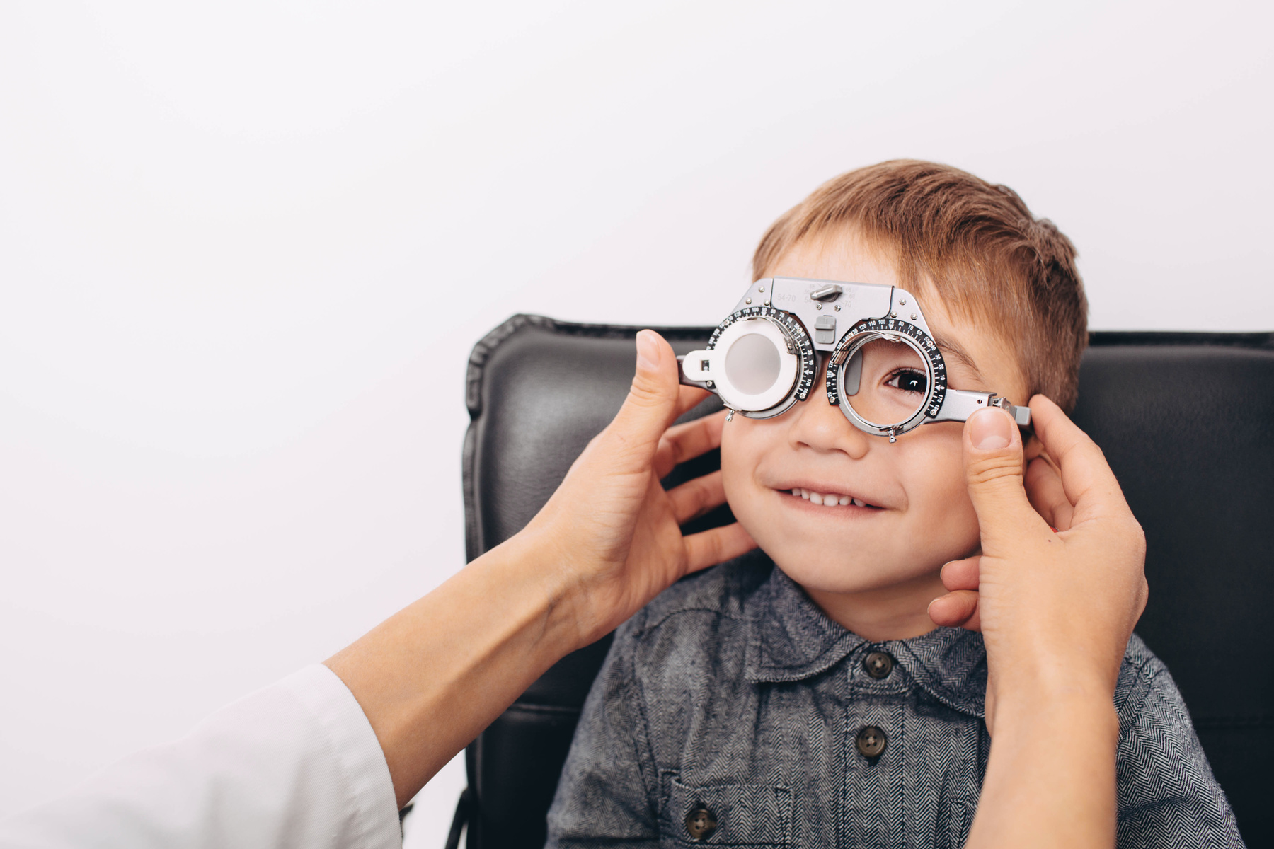 optometrist making an eye test to little cute boy happy pediatric eye patients receving exams at Specs Eye Care in Chattanooga TN